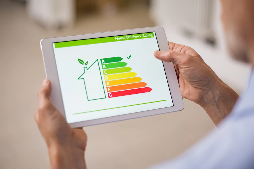 hand-holding-digital-tablet-and-looking-at-house-efficiency-rating