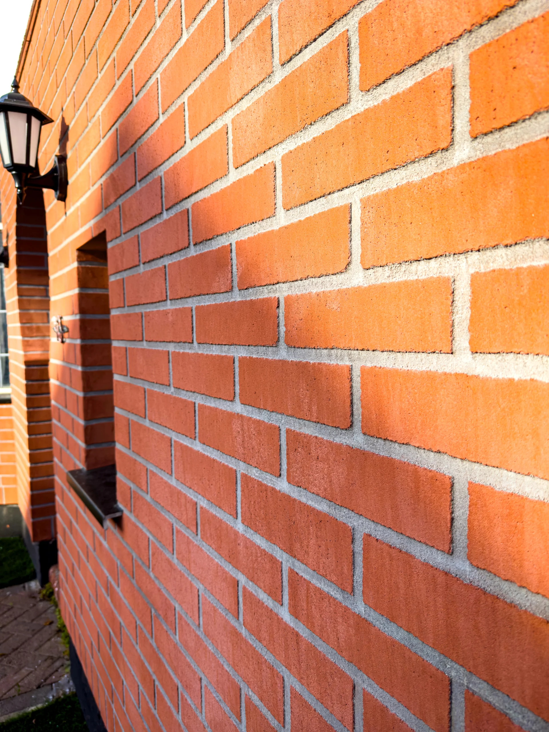 Close-up view of a freshly finished red brick exterior wall with clean mortar lines and sunlight casting shadows