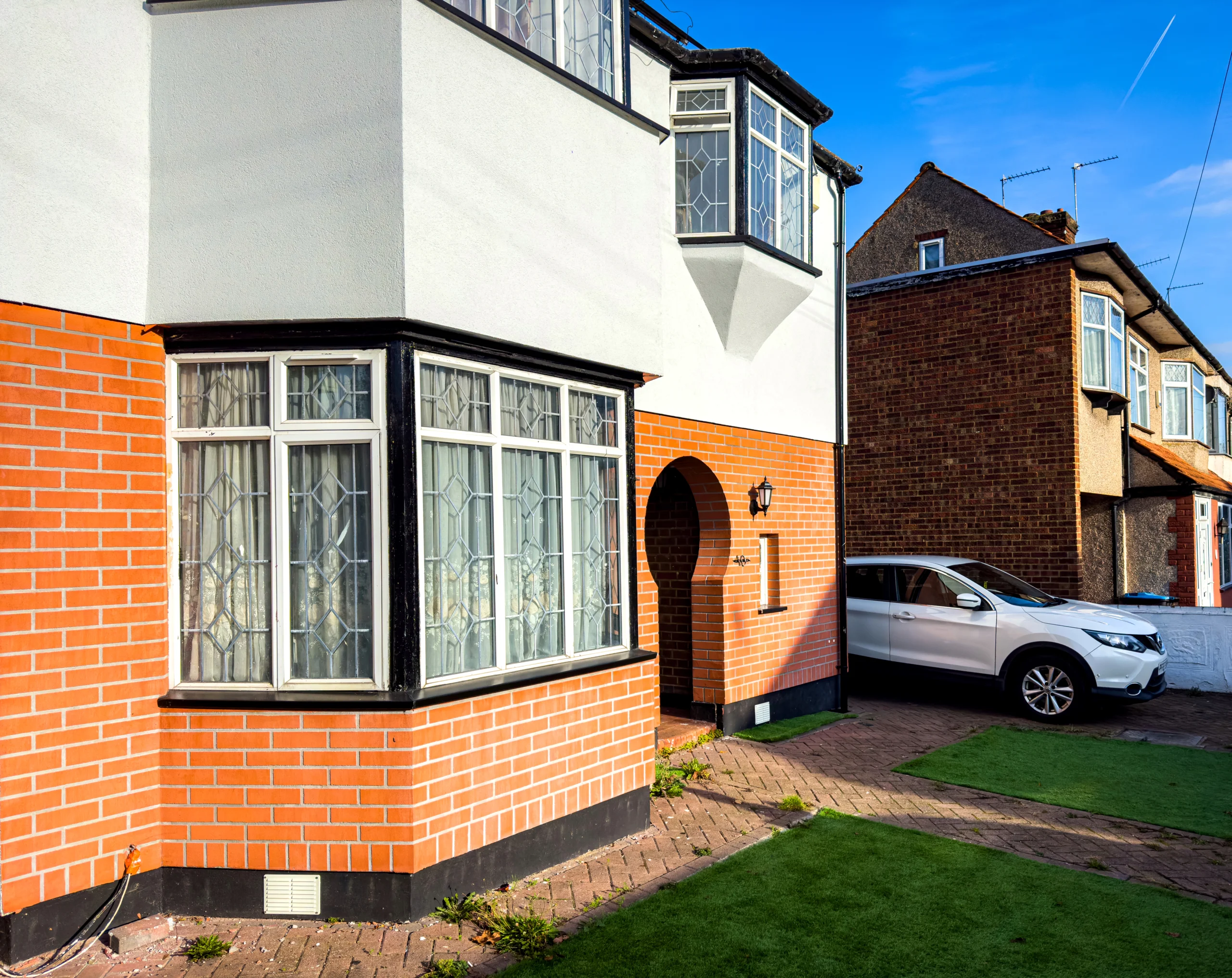 Front view of a semi-detached house with red brick and white exterior walls