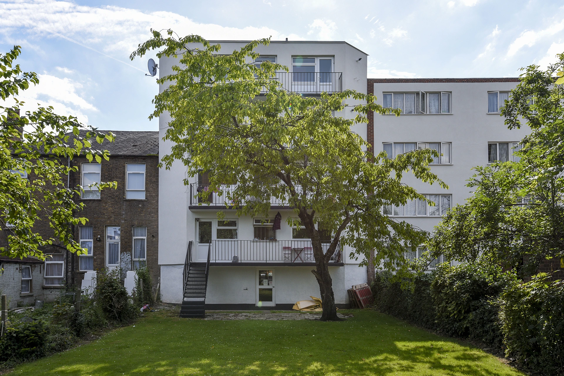 Rear view of the same apartment building after external insulation installation, showing a smooth white façade and fresh appearance