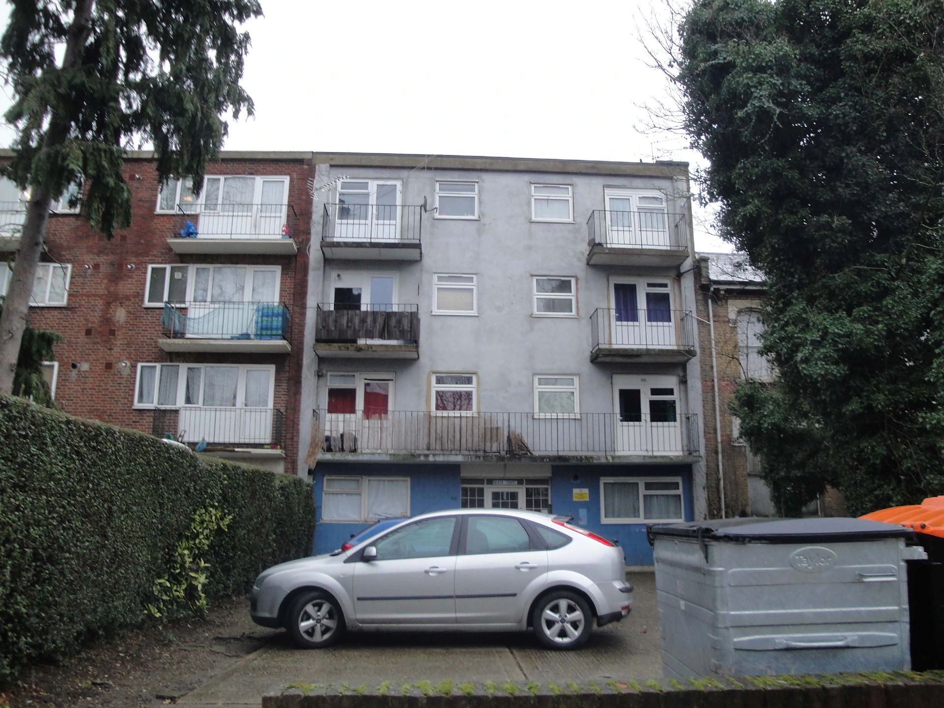 Old three-storey residential block with cracked walls and peeling paint before renovation