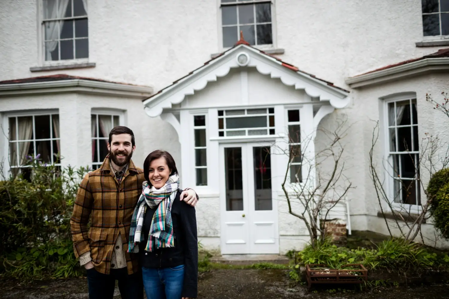 portrait couple standing near new house