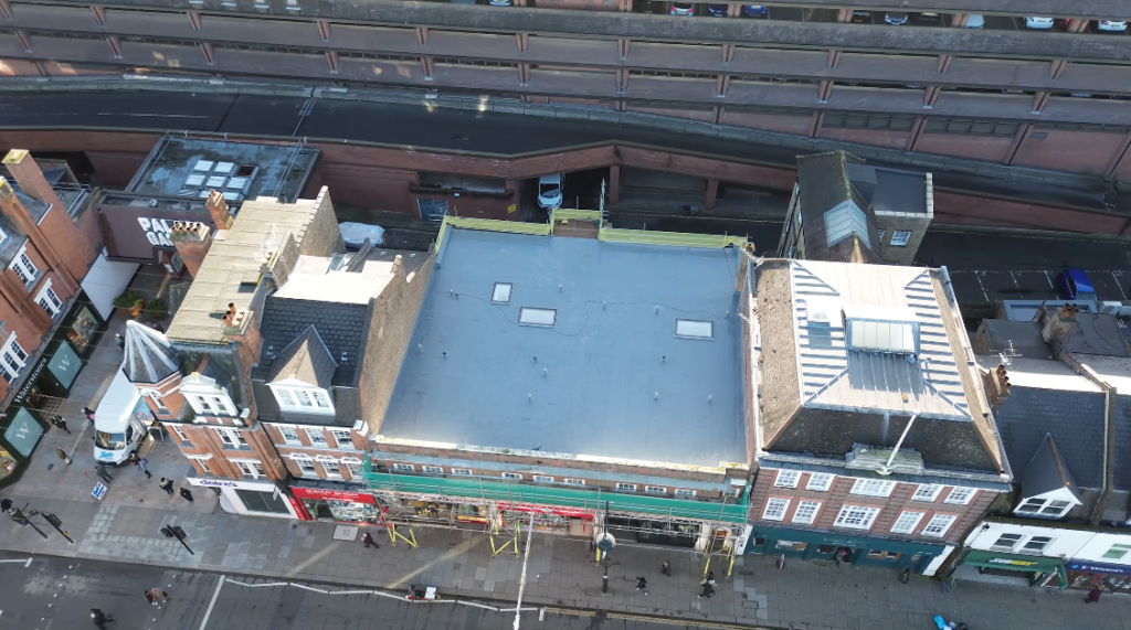 Aerial view of completed flat roof installation above high street shops