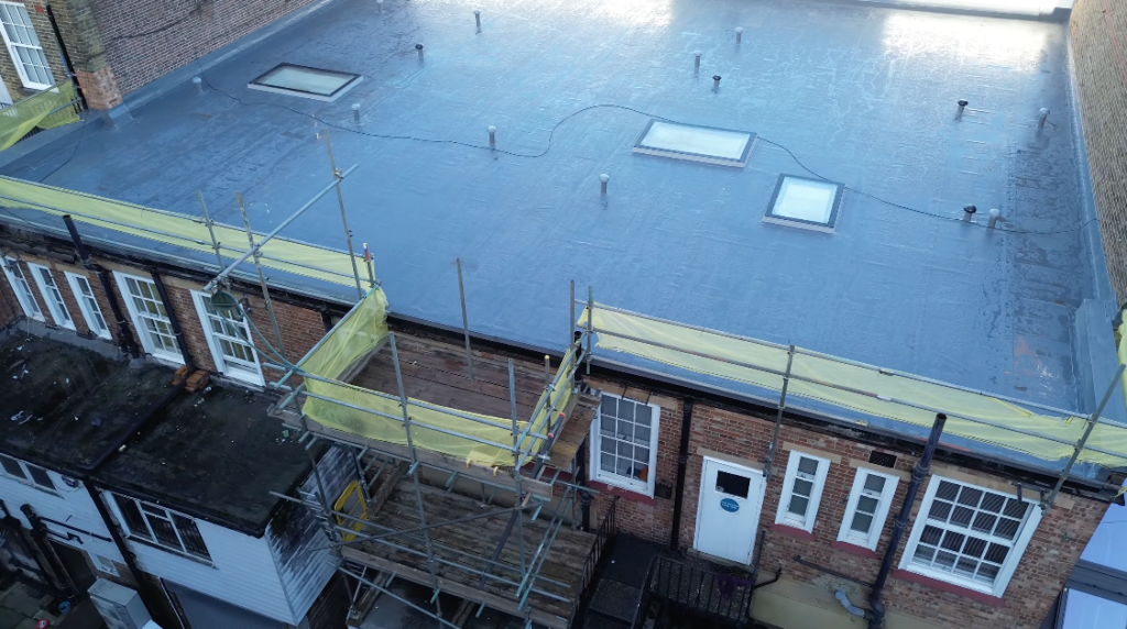Flat roof refurbishment with scaffolding and rooflights on commercial building