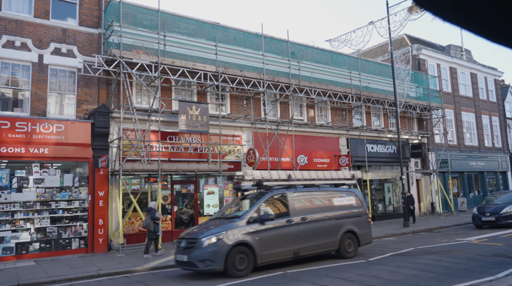 Street view of scaffolding installed across retail units for roofing project