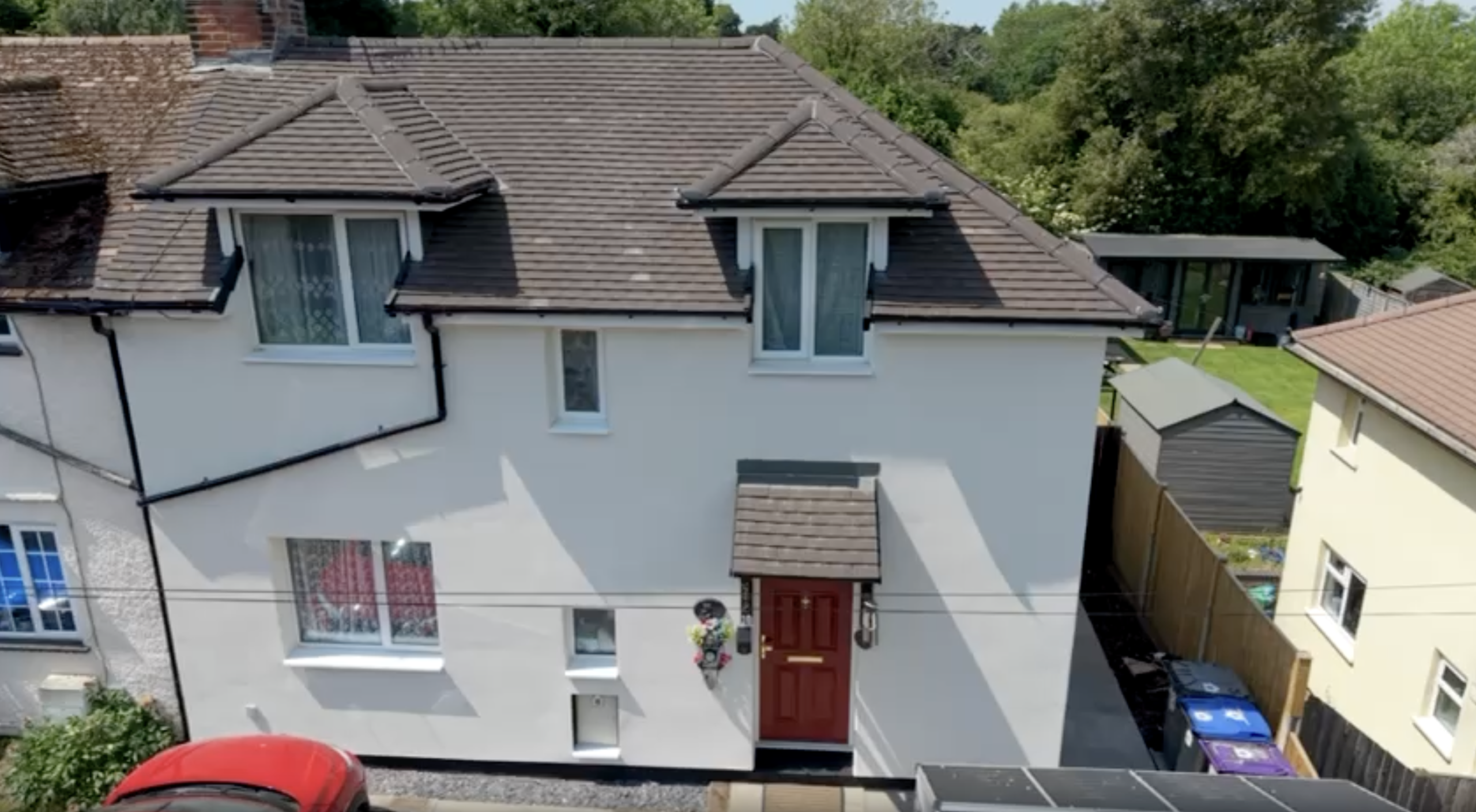 An aerial, eye-level shot shows a two-story semi-detached house with a newly insulated and rendered off-white exterior wall in Hitchin.